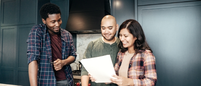 Husband and wife in kitchen with technician smiling at paper document