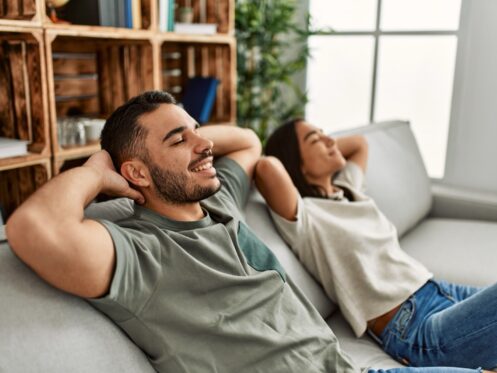 A couple enjoying their home HVAC system, relaxing on the couch.